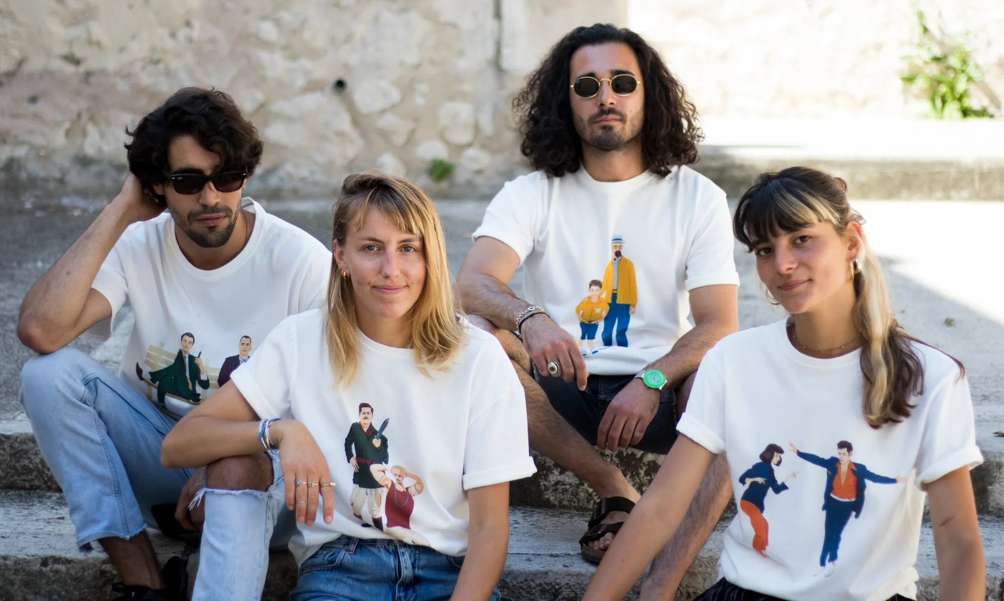 Four friends sitting on stone steps, all wearing WAAS Iconic Collection tees